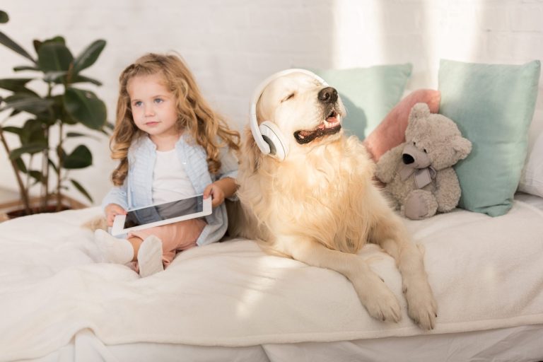 cohabitation chien-enfant assis sur un lit avec une tablette et un écouteur