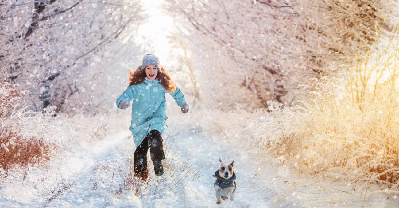petite fille qui court avec son chien en hiver